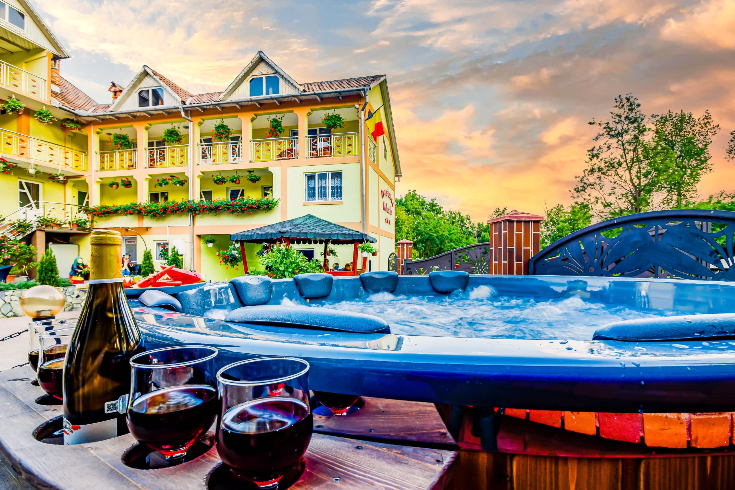 Vilă cu jacuzzi și sticle de vin la apus.